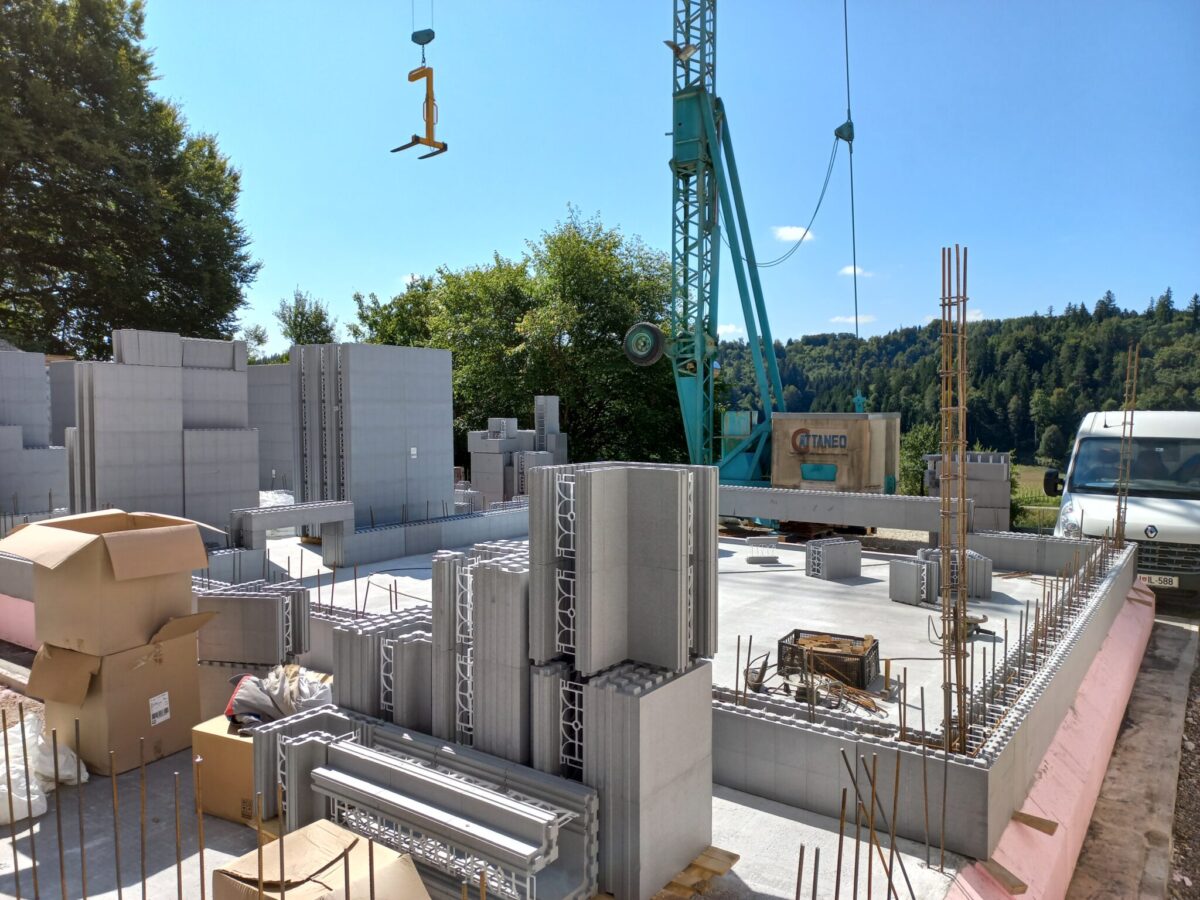 Napredni gradbeni sistem, montaža zidnih elementov na temeljno ploščo s pomočjo dvigala, primer energijsko učinkovite gradnje.